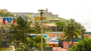 Maisons colorées, palmiers et fort historique surplombant l'océan dans les Caraïbes.