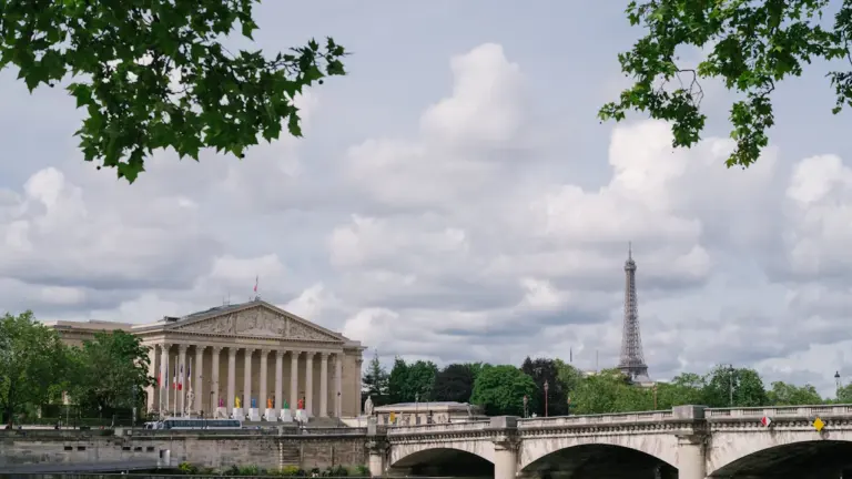 Vue panoramique de l'Assemblée nationale à Paris avec la Seine au premier plan.
