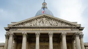 Façade néoclassique d'un bâtiment officiel français avec le drapeau tricolore au sommet.
